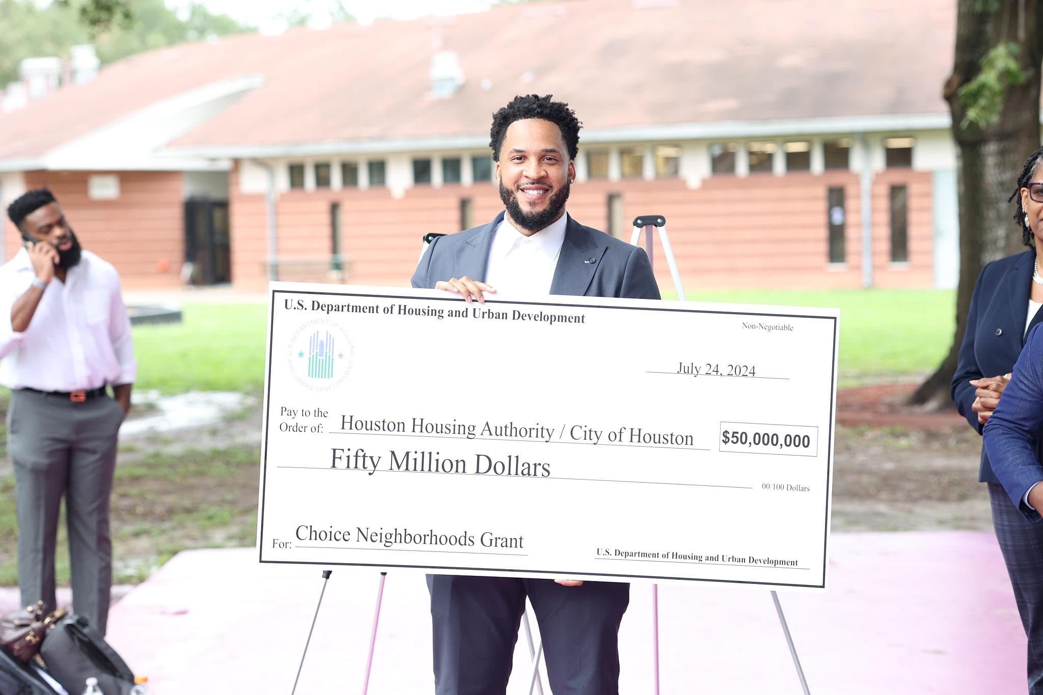 Brandon Rule holding a $50,000,000 HUD Choice Neighborhoods Grant check for the Houston Housing Authority